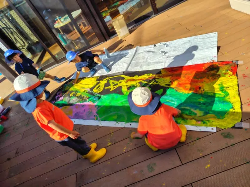 Children painting on a large canvas on the terrace